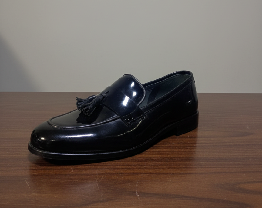 Black loafer shoe on a wooden surface with a plain background
